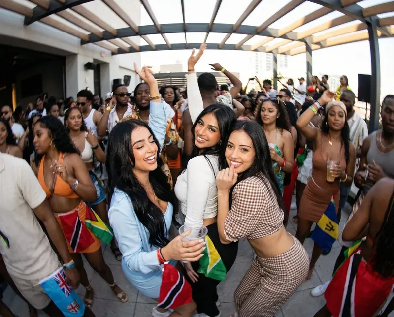 Three friends laughing in the middle of a packed Soca Forever party