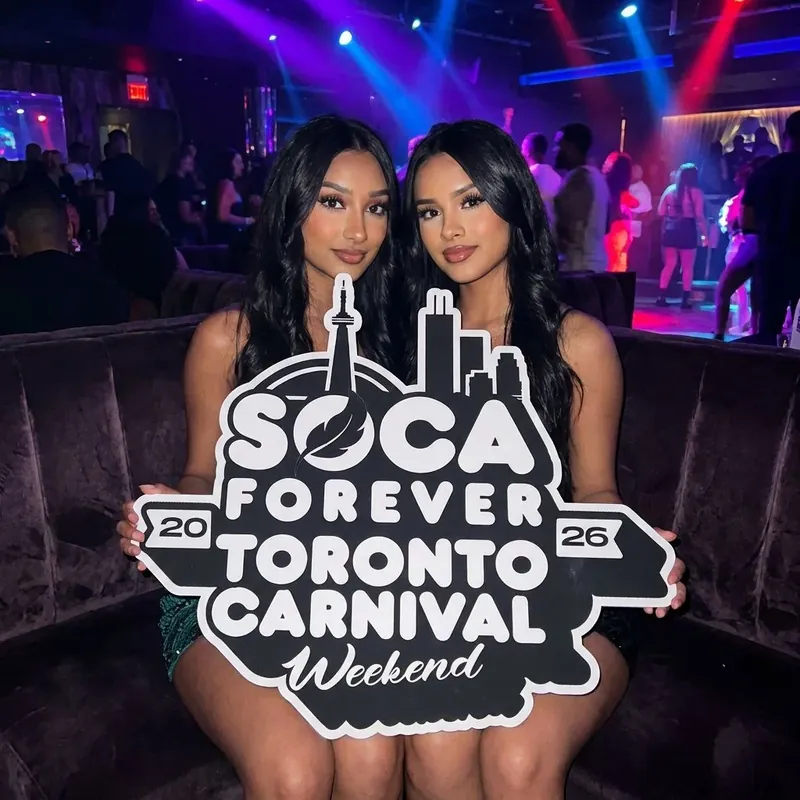 Soca Forever guests with the sign, dancefloor visible behind them
