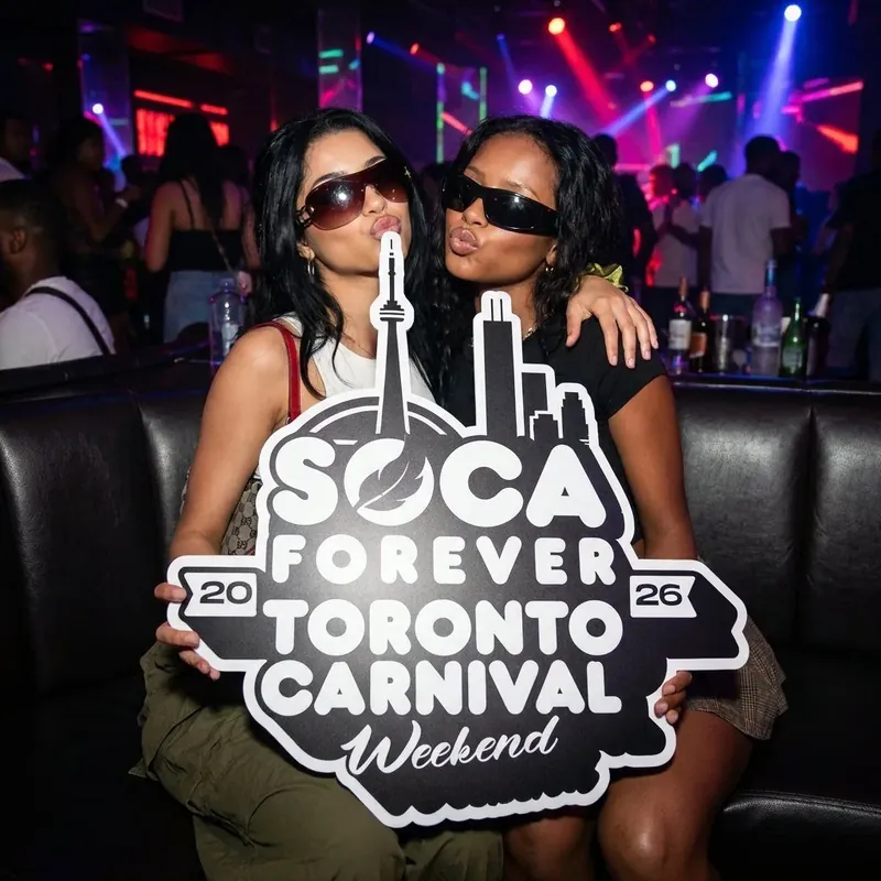 Disco-ball night fete with attendees holding the Soca Forever Toronto Carnival sign