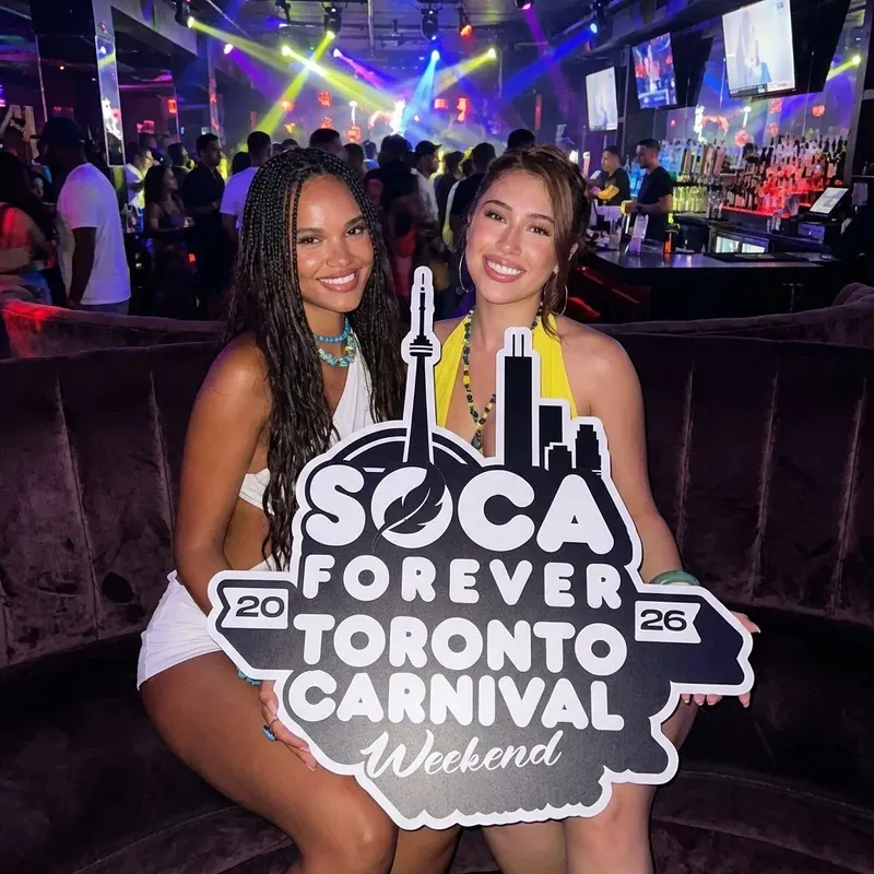 Two friends in sunglasses with the Soca Forever sign at a downtown nightclub